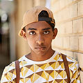 a somber boy wearing a backwards baseball cap looks at the camera