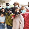 Diverse group of adolescents standing together while wearing face masks. 