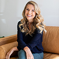 Kristina Saffran sitting on a chair smiling. 